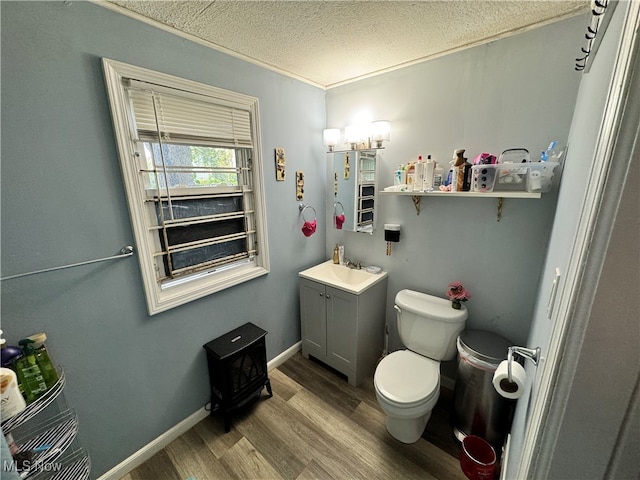 bathroom featuring toilet, hardwood / wood-style floors, a textured ceiling, ornamental molding, and vanity