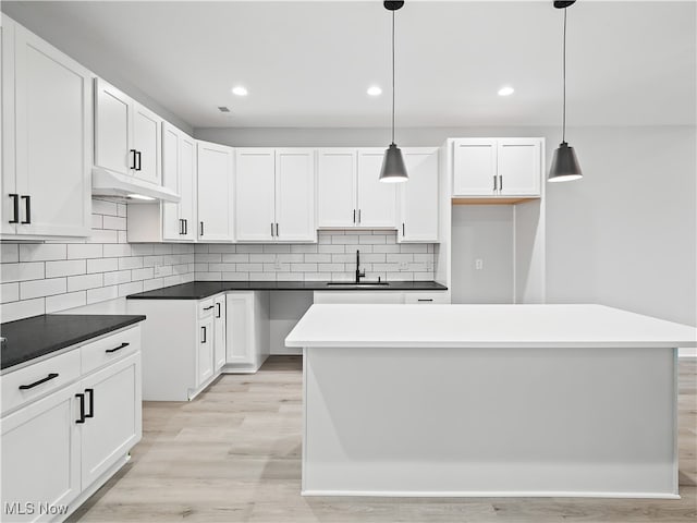 kitchen with hanging light fixtures, sink, and white cabinetry