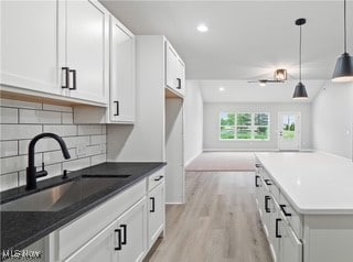 kitchen featuring light hardwood / wood-style flooring, hanging light fixtures, sink, and white cabinets