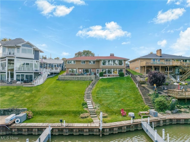 rear view of house featuring a water view and a lawn