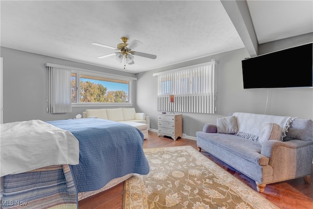 bedroom with ceiling fan, beamed ceiling, and hardwood / wood-style flooring