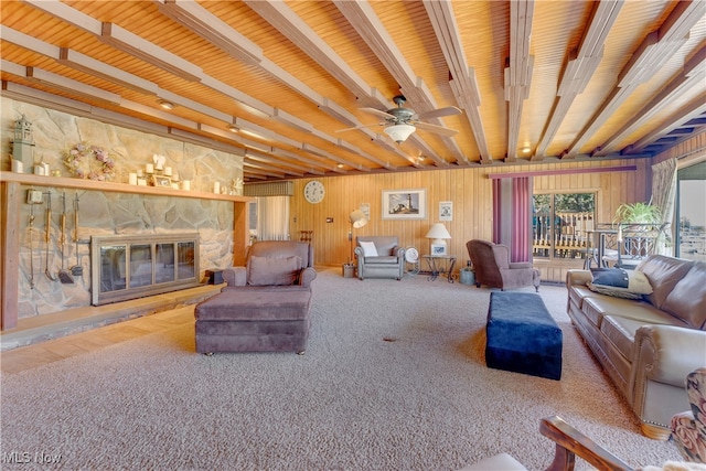 living room featuring beamed ceiling, ceiling fan, wooden ceiling, wooden walls, and a fireplace