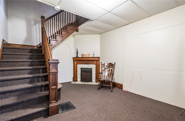 stairway featuring a fireplace, a paneled ceiling, and carpet flooring