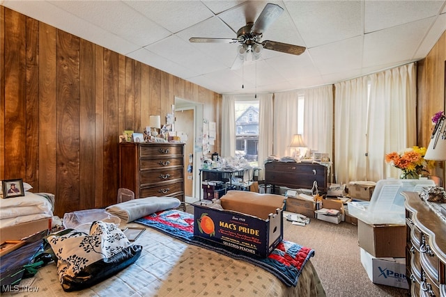 carpeted bedroom with wood walls and ceiling fan