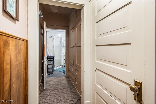 corridor featuring wooden walls and carpet