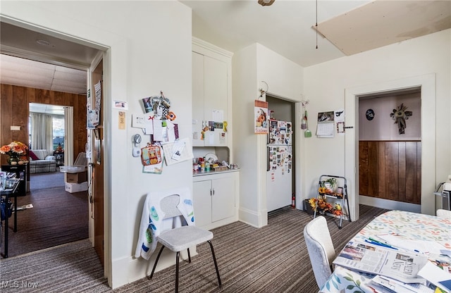 bedroom featuring wooden walls, white refrigerator, and dark carpet