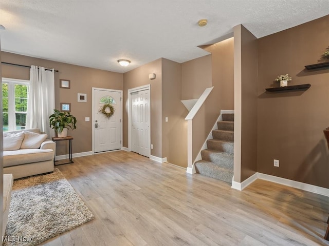 foyer entrance with light wood-type flooring and a textured ceiling