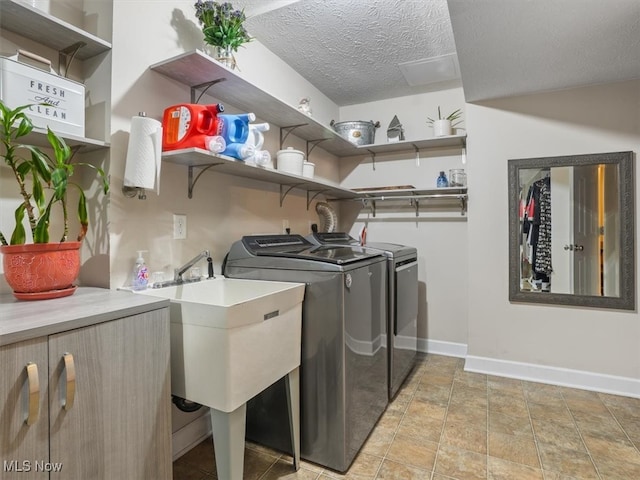 washroom with independent washer and dryer, sink, and a textured ceiling