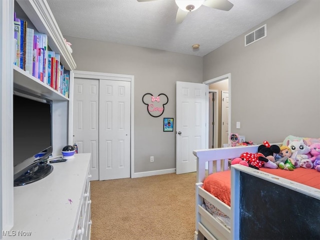 bedroom featuring light carpet, a closet, a textured ceiling, and ceiling fan