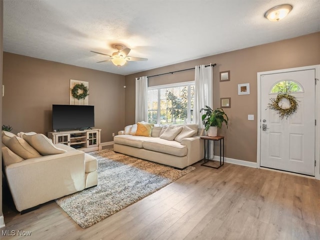 living room featuring light hardwood / wood-style flooring, a textured ceiling, and ceiling fan