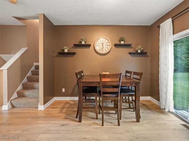 dining space with light hardwood / wood-style flooring and a textured ceiling