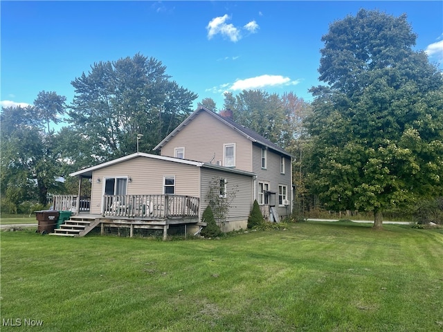 rear view of house with a wooden deck and a lawn