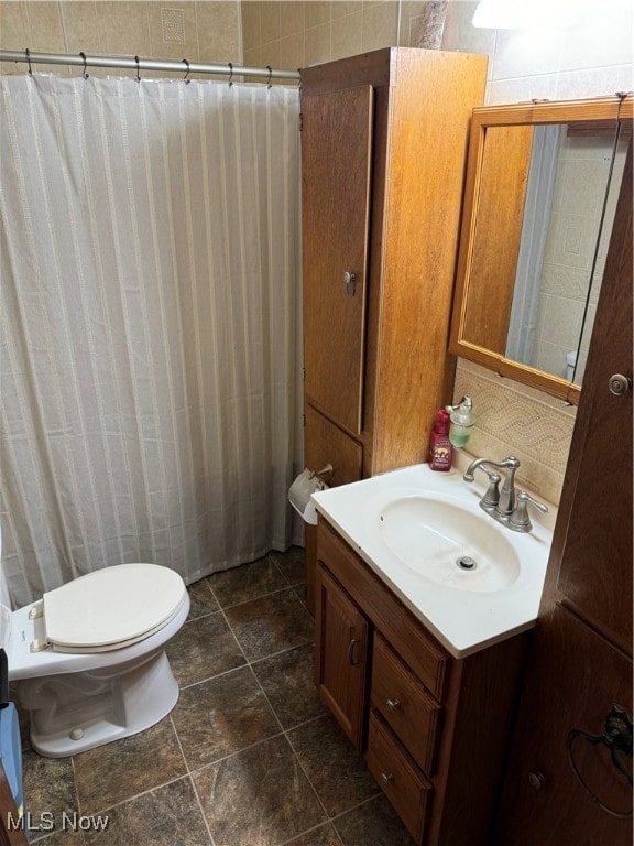 bathroom with vanity, walk in shower, toilet, and tile walls