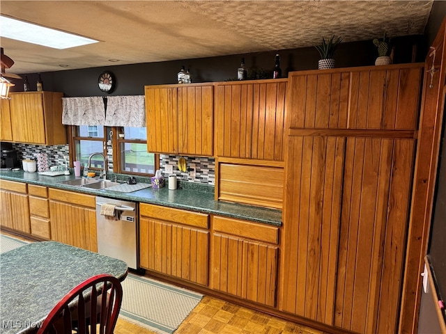 kitchen featuring a skylight, decorative backsplash, sink, and dishwasher