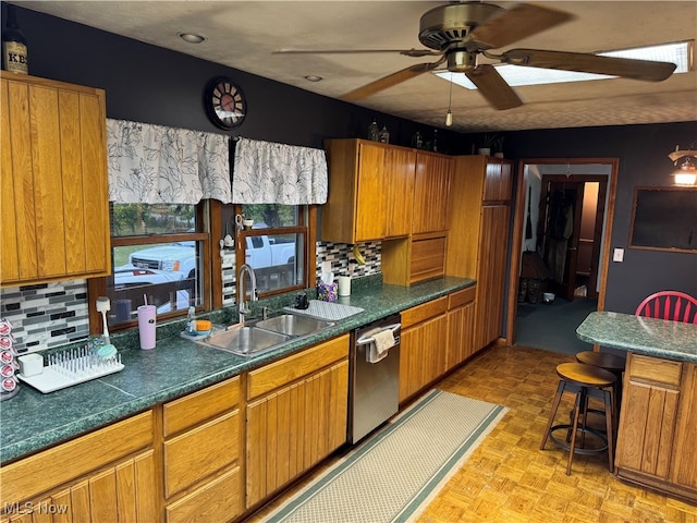 kitchen featuring ceiling fan, tasteful backsplash, sink, a kitchen bar, and stainless steel dishwasher