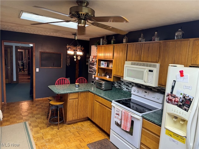 kitchen featuring white appliances, light parquet floors, a kitchen breakfast bar, kitchen peninsula, and backsplash