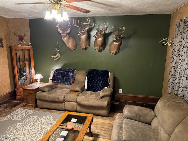 living room featuring ceiling fan, wood-type flooring, and a textured ceiling