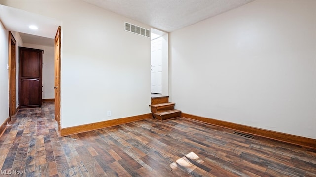 spare room with dark hardwood / wood-style floors and a textured ceiling