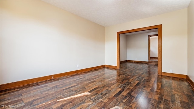 empty room featuring dark hardwood / wood-style flooring and a textured ceiling