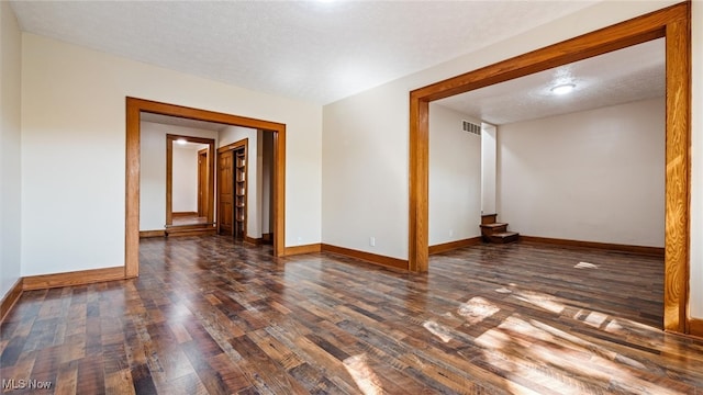 empty room featuring dark wood-type flooring and a textured ceiling