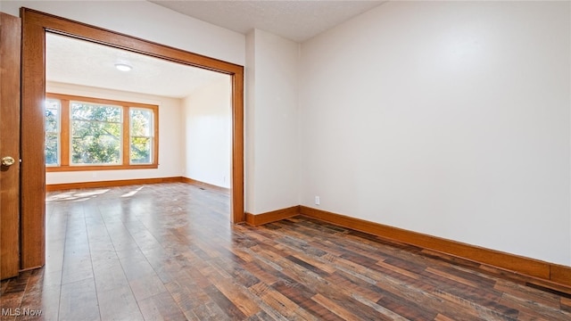 spare room featuring a textured ceiling and dark wood-type flooring