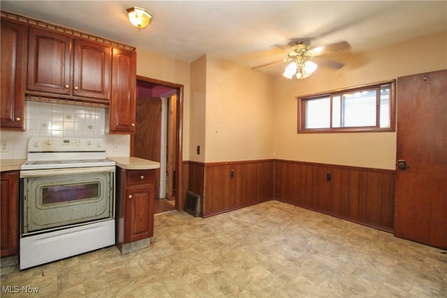 kitchen featuring white electric range oven, ceiling fan, decorative backsplash, and wood walls