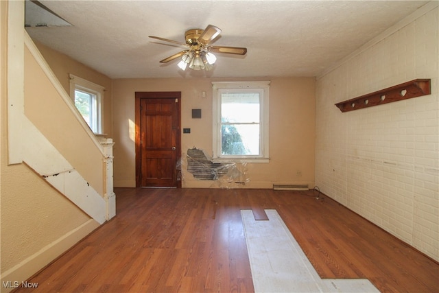 entrance foyer with wood-type flooring, brick wall, and a healthy amount of sunlight