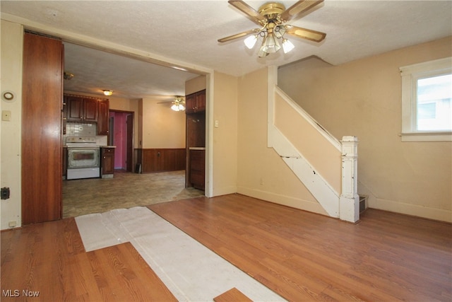 interior space with wood-type flooring, a textured ceiling, wood walls, and ceiling fan