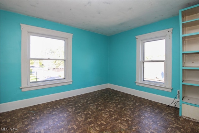 spare room with dark parquet floors and a wealth of natural light