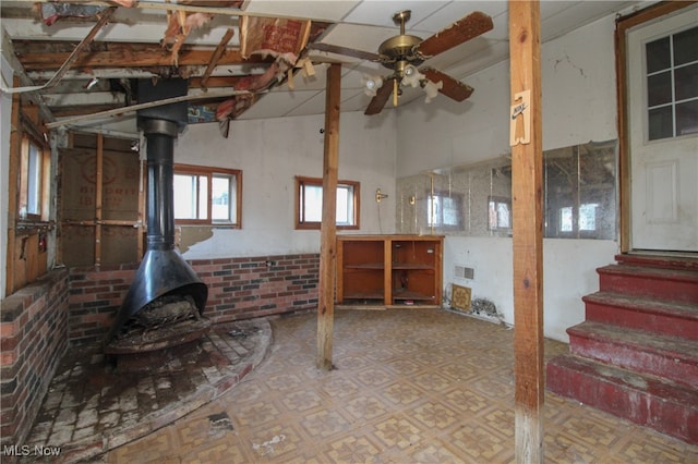 basement featuring ceiling fan and a wood stove