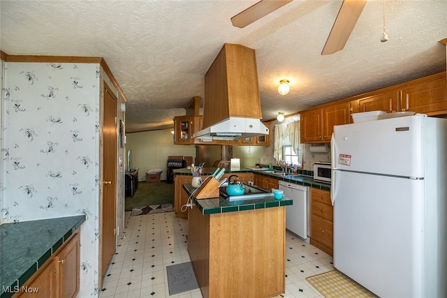 kitchen with ventilation hood, a textured ceiling, white appliances, and a center island