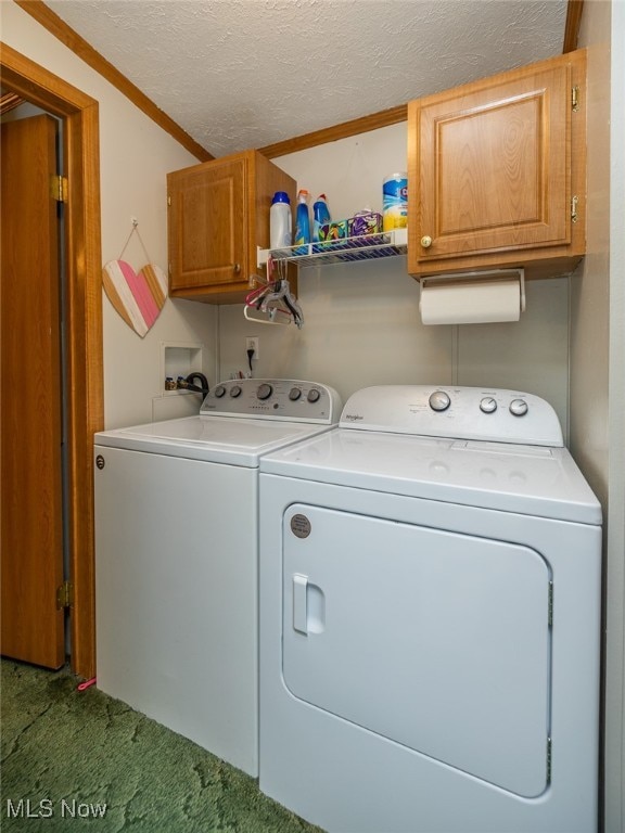 clothes washing area featuring carpet flooring, cabinets, washer and clothes dryer, ornamental molding, and a textured ceiling