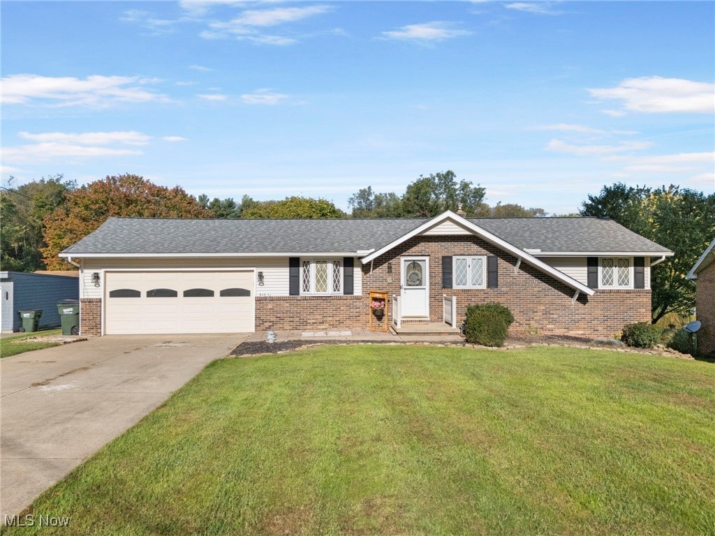 ranch-style house featuring a garage and a front lawn