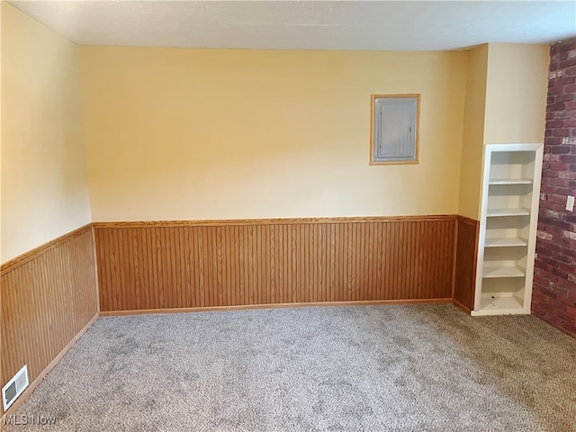 carpeted empty room with electric panel and wooden walls