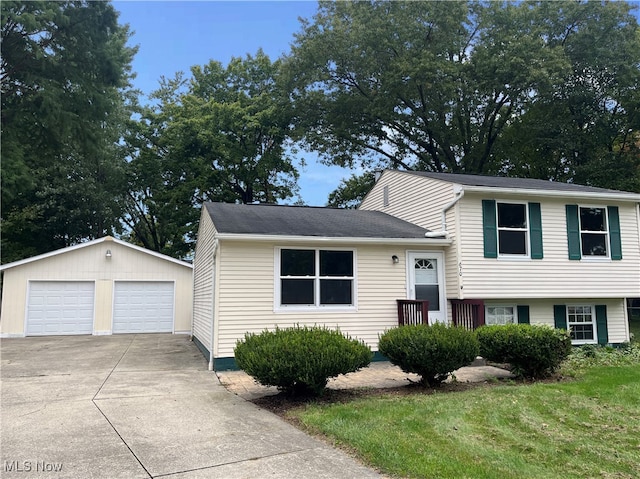 split level home featuring a garage, a front lawn, and an outbuilding