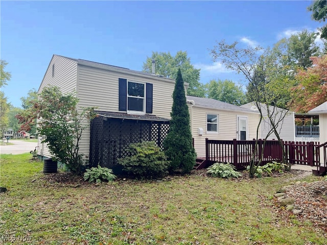 rear view of house featuring a wooden deck and a lawn