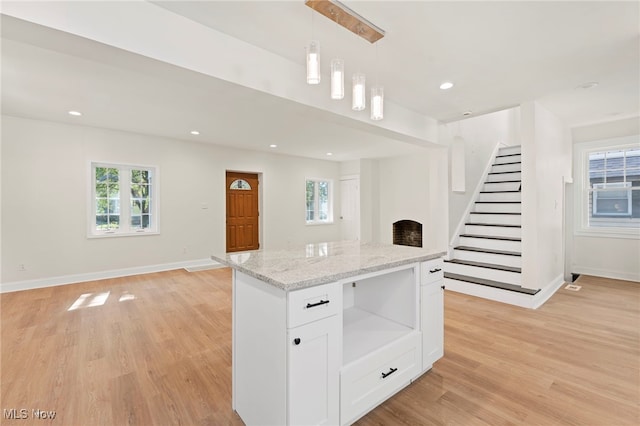 kitchen with white cabinets, decorative light fixtures, light hardwood / wood-style floors, and a wealth of natural light