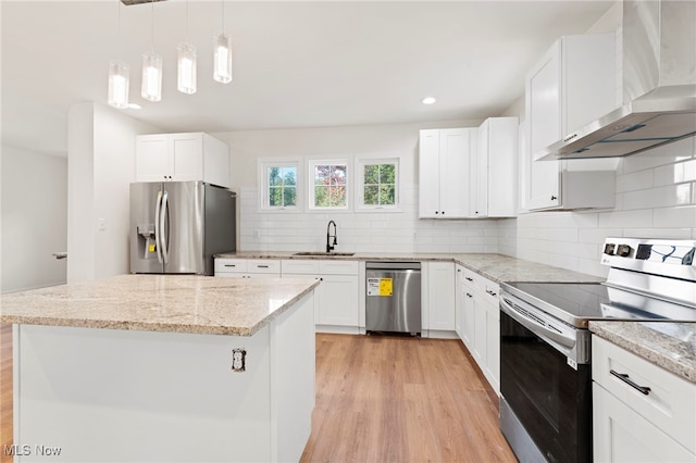 kitchen featuring wall chimney range hood, white cabinetry, sink, and stainless steel appliances