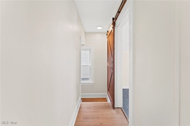 hallway featuring light wood-type flooring and a barn door