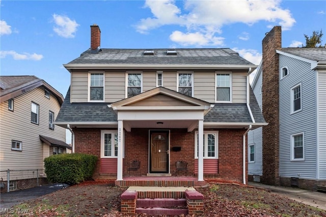 view of front of house featuring a shingled roof, a porch, and brick siding