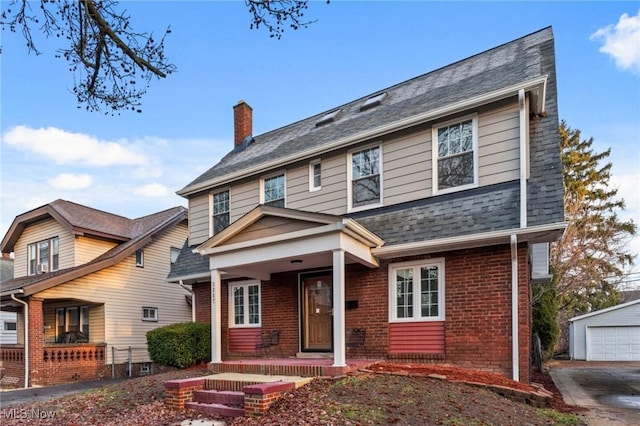 view of front of house with a porch, brick siding, a shingled roof, an outdoor structure, and a chimney