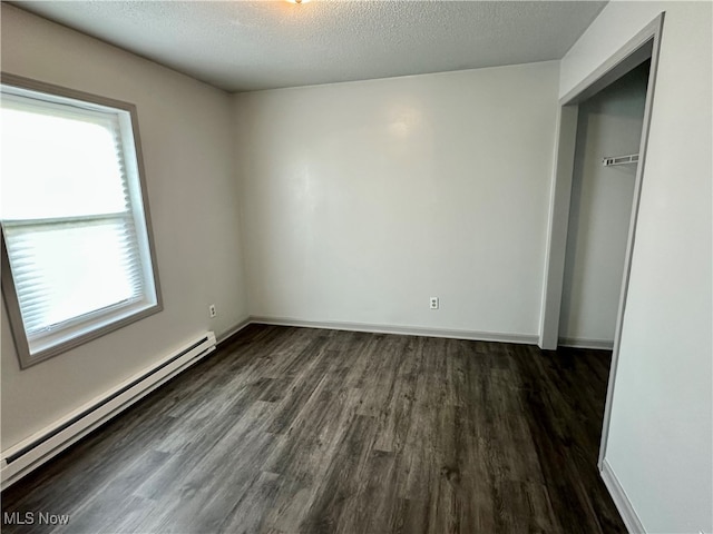 unfurnished bedroom featuring dark wood-type flooring, a closet, a baseboard heating unit, and a textured ceiling