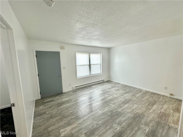 unfurnished room featuring baseboard heating, hardwood / wood-style flooring, and a textured ceiling