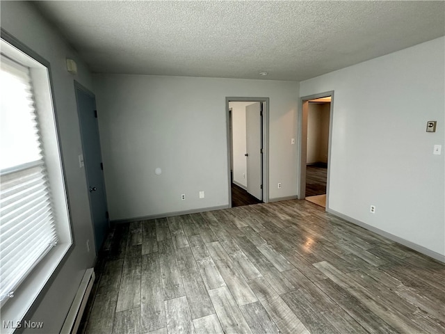 unfurnished bedroom featuring multiple windows, wood-type flooring, and a textured ceiling