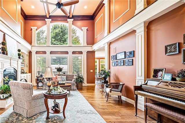 living room featuring ornamental molding, light hardwood / wood-style flooring, ceiling fan, and ornate columns