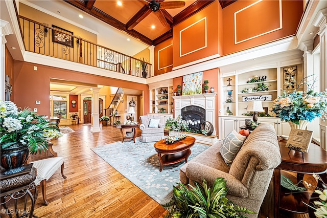 living room with decorative columns, crown molding, light hardwood / wood-style floors, and beam ceiling