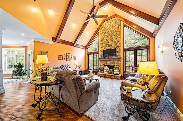 living room featuring a stone fireplace, hardwood / wood-style flooring, decorative columns, high vaulted ceiling, and ceiling fan