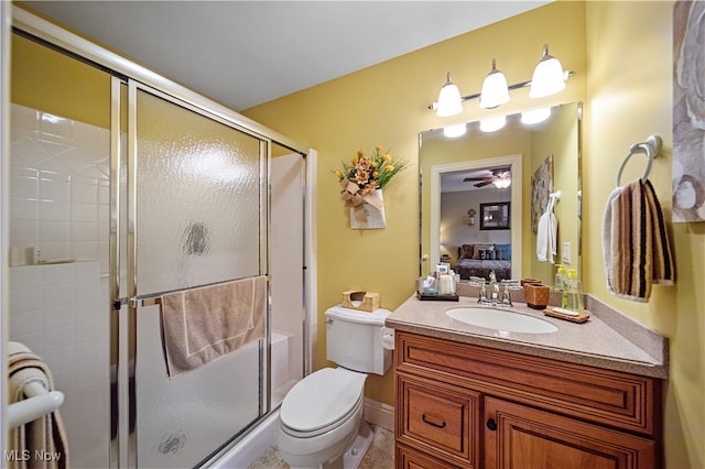 bathroom featuring vanity, ceiling fan, toilet, and a shower with door