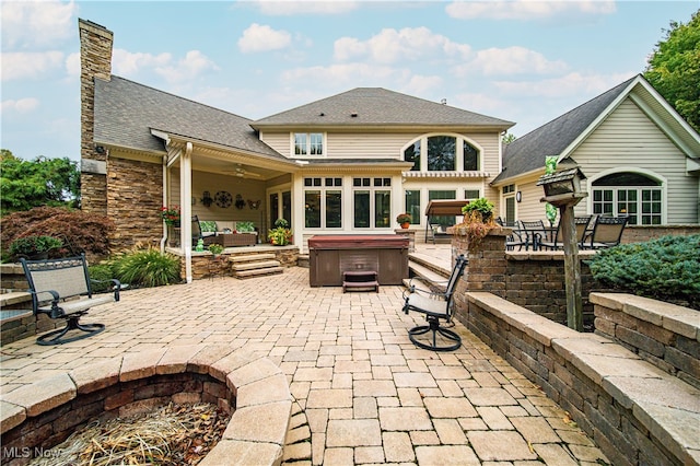 rear view of house with a hot tub, a patio, and an outdoor living space