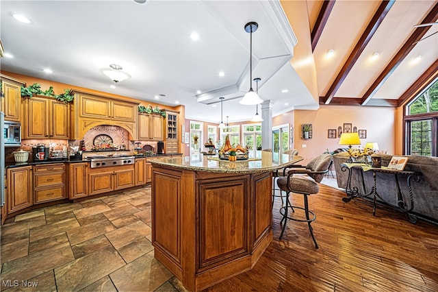 kitchen with vaulted ceiling with beams, a breakfast bar area, a kitchen island, appliances with stainless steel finishes, and decorative light fixtures